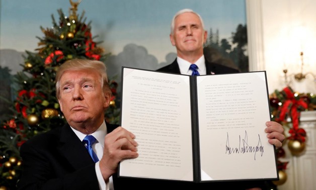 Vice President Mike Pence stands behind as President Donald Trump holds up the proclamation he signed that the United States recognizes Jerusalem as the capital of Israel and will move its embassy there, during an address from the White House in Washingto