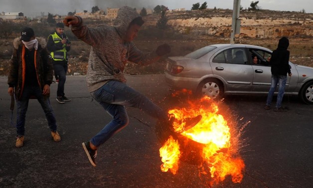 A Palestinian kicks a burning tire during clashes with Israeli troops at a protest against U.S. President Donald Trump's decision to recognize Jerusalem as Israel's capital, near the Jewish settlement of Beit El, near the West Bank city of Ramallah Decemb
