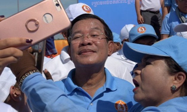 © Tang Chhin Sothy, AFP | Cambodia's Prime Minister Hun Sen (C) poses for selfies with supporters of the Cambodian People's Party (CPP) on the last day of the commune election campaign in Phnom Penh on June 2, 2017.
