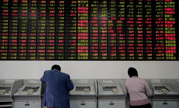 FILE PHOTO - Investors look at computer screens showing stock information at a brokerage house in Shanghai, China November 24, 2017. REUTERS/Aly Song
