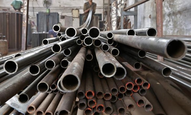A worker stacks steel pipes - Reuters