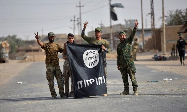 Shi'ite Popular Mobilization Forces (PMF) fighters carry the Islamic State militants flag downward after liberating the city of Al-Qaim, Iraq November 3, 2017. REUTERS/Stringer