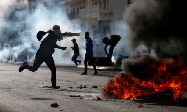 A Palestinian demonstrator hurls stones towards Israeli troops during clashes at a protest against Donald Trump's decision to recognize Jerusalem as the capital of Israel, December 11, 2017. REUTERS/Mohamad Torokman