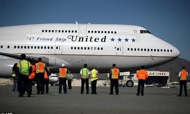 Workers look on as United Airlines Flight 747 preapres to take off from San Francisco International Airport for its final flight to Honolulu, Hawaii -- one of the last before United retires its entire Boeing 747 fleet