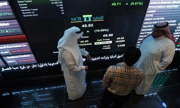 Investors talk with each other as they monitor a screen displaying stock information at the Saudi Stock Exchange (Tadawul) in Riyadh – Reuters 