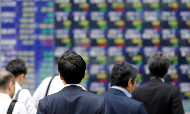 People walk past an electronic stock quotation board outside a brokerage in Tokyo, Japan, September 22, 2017. REUTERS/Toru Hanai/File Photo