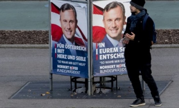 © AFP/File | A man stands by a poster of Norbert Hofer, presidential candidate for Austria's right-wing Freedom Party (FPOe), outside the Austrian parliament in November
