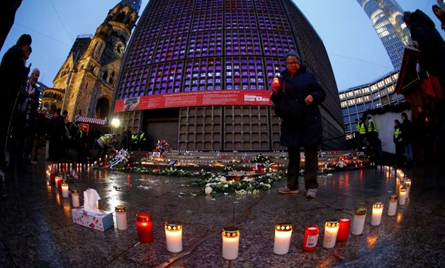 A woman places a candle at the memorial at the site of last year's truck attack on a Christmas market, which killed 12 people and injured many others, at Breitscheidplatz square in Berlin, Germany December 19, 2017. Picture taken with a fisheye lens. REUT