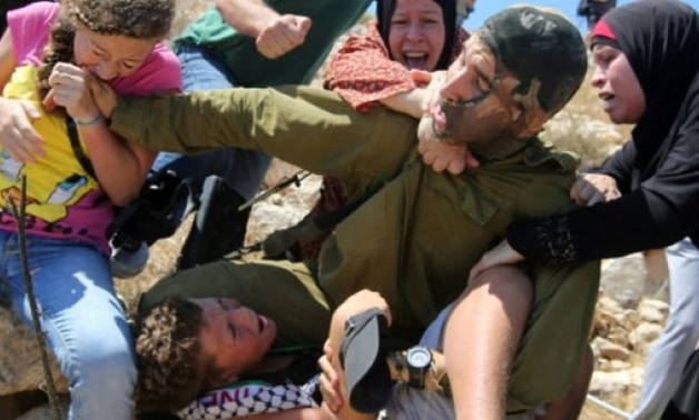 © AFP/File | This photo taken on August 28, 2015 shows Palestinian Ahed Tamimi (L) fighting with other members of her family to free a Palestinian boy held by an Israeli soldier during clashes in the West Bank village of Nabi Saleh near Ramallah
