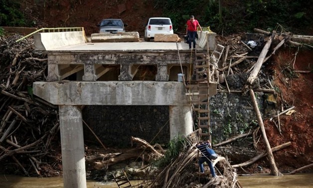 A woman looks as her husband climbs down a ladder at a partially destroyed bridge, after Hurricane Maria hit the area in September, in Utuado, Puerto Rico November 9, 2017. REUTERS/Alvin Baez