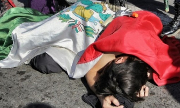 © AFP/File | An activist posing as a murder victim lies on the ground during a demonstration in Ciudad Juarez against the approval of a new internal security law that would formalize the military's role in domestic security
