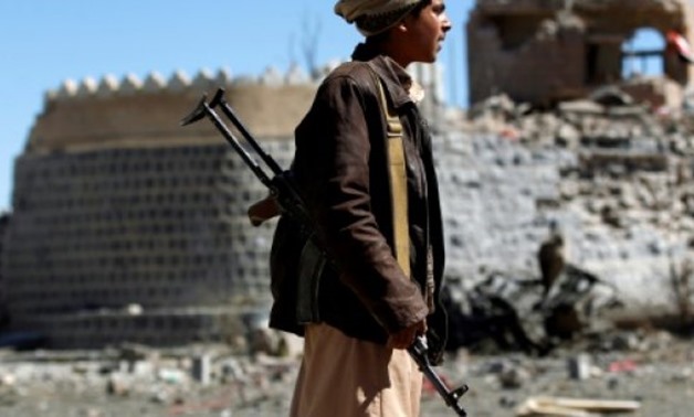 © AFP | An armed Yemeni youth looks at the debris following a reported air strike by the Saudi-led coalition in southern Sanaa on December 25, 2017
