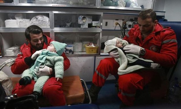 Syrian paramedics hold children in an ambulance on the second night of an evacuation operation in Douma in the Eastern Ghouta region late on December 27, 2017 - AFP