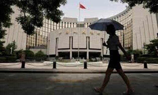 FILE PHOTO: A woman walks past the headquarters of the People's Bank of China (PBOC), the central bank, in Beijing, June 21, 2013. REUTERS/Jason Lee/File Photo