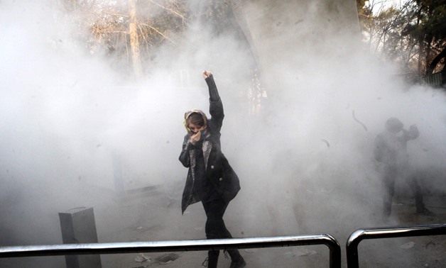 An Iranian woman raises her fist amid the smoke of tear gas at the University of Tehran during a protest driven by anger over economic problems, in the capital Tehran on December 30, 2017- AFP.