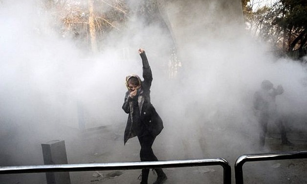 A woman raises her fist amid tear gas at the University of Tehran during a protest on December 30, 2017 - AFP
