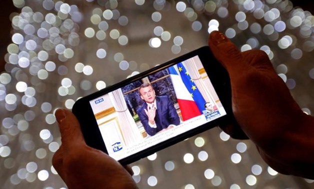 French President Emmanuel Macron is seen on the screen of an iPhone in Marseille, as he gives the traditional New Year speech during a prime time news broadcast at the Elysee Palace in Paris, France, December 31, 2017. REUTERS/Jean-Paul Pelissier