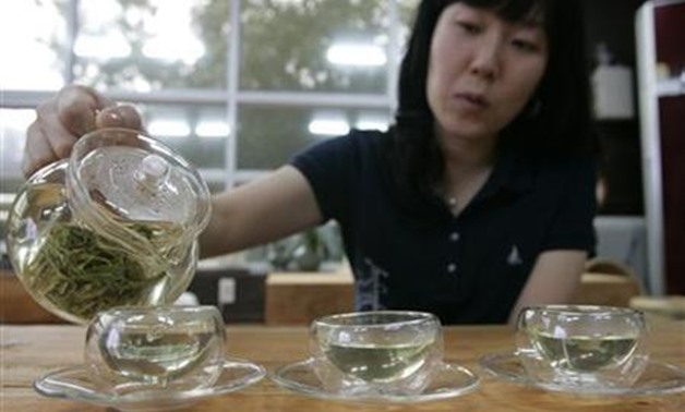 A woman pours hot water to make green tea at a traditional tea house in Boseong - Reuters 