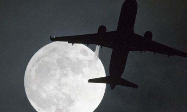 Justin Tallis, AFP | A plane flys in front of a "super moon" or "wolf moon" on its approach to London Heathrow Airport on January 1, 2018.