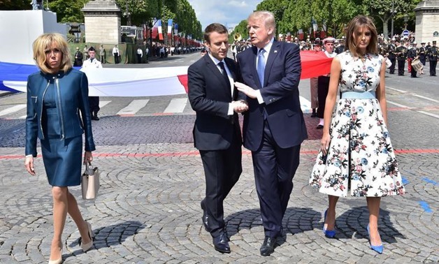 French President Emmanuel Macron (2ndL) shakes hands with U.S. President Donald Trump, next to Macron's wife Brigitte Macron (L) and U.S. First Lady Melania Trump during the traditional Bastille Day military parade on the Champs-Elysees avenue in Paris, F