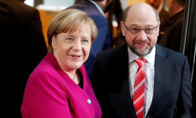 Leader of the Christian Democratic Union (CDU) and the acting German Chancellor Angela Merkel and Social Democratic Party (SPD) leader Martin Schulz shakes hands before exploratory talks about forming a new coalition government at the SPD headquarters in 