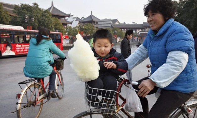 FILE PHOTO - A woman carries her grandchild in the basket of her bicycle at the end of a temple fair for the celebration of the last day of Chinese New Year, outside the Longhua temple in Shanghai February 21, 2008. REUTERS/ Nir Elias
