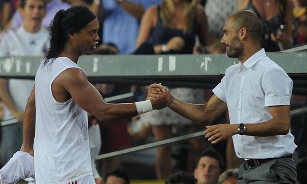 Barcelona's coach Pep Guardiola (L) greets AC Milan's player Ronaldinho after his substitution during a friendly match at Camp Nou stadium in Barcelona August 25, 2010. REUTERS/Albert Gea (SPAIN - Tags: SPORT SOCCER)