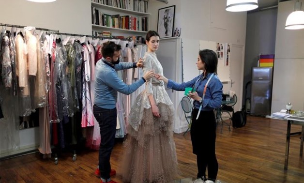 French designer Julien Fournie (L) adjusts a creation on model Greta (C) during a fitting at his workshop ahead of his Spring-Summer 2018 Haute Couture fashion show presentation in Paris, France, January 15, 2018. Picture taken January 15, 2018. REUTERS/C