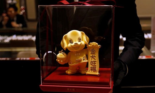 FILE PHOTO: A staff poses with a dog-shaped gold figurine, at Chow Tai Fook Jewellery store ahead of the Lunar Year of the Dog in Hong Kong, China December 14, 2017. REUTERS/Tyrone Siu/File Photo