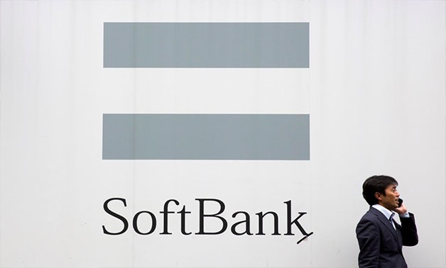 A man talks on the phone as he stand in front of an advertising poster of the SoftBank telecommunications company in Tokyo October 16, 2015 - REUTERS/Thomas Peter/File Photo