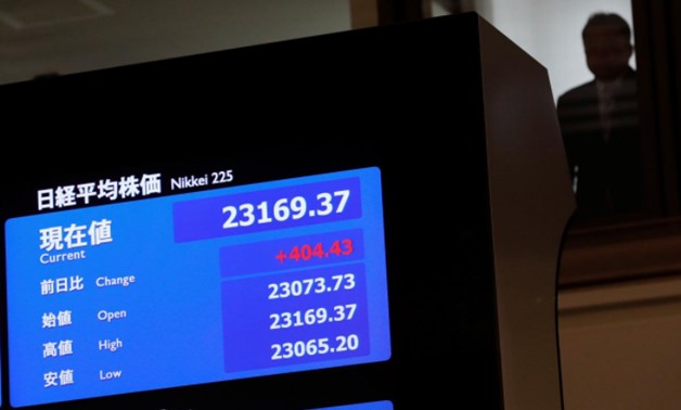 A man is seen behind an electronic board displaying the Nikkei average after the ceremony which kicks off the first day of trading in 2018 at the Tokyo Stock Exchange in Tokyo, Japan January 4, 2018. REUTERS/Kim Kyung-Hoon