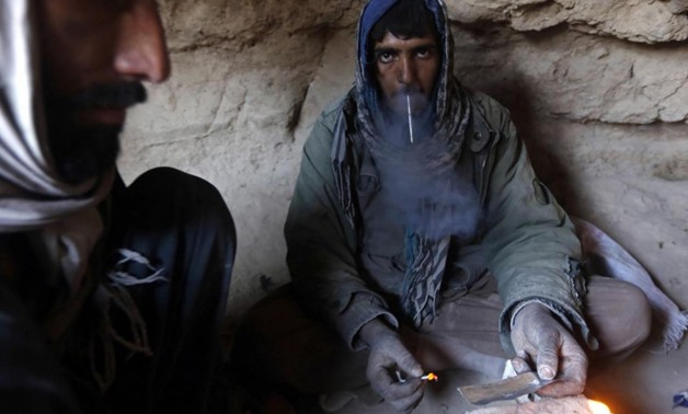A drug addict smokes heroin inside a cave in Farah province February 4, 2015. REUTERS/Omar Sobhani
