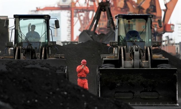 FILE PHOTO - An employee walks between front-end loaders which are used to move coal imported from North Korea at Dandong port in the Chinese border city of Dandong, Liaoning province December 7, 2010. REUTERS/Stringer/