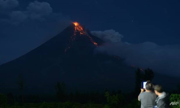 Tourists taking photos of Mayon volcano spewing lava ash from its crater, as seen in Daraga town, south of Manila - AFP/Ted ALJIBE