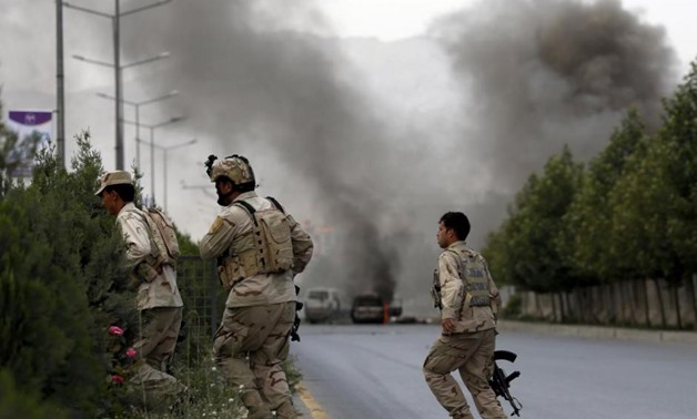 Members of Afghan security forces cross a road as smoke billows from the site of an attack near the Afghan parliament in Kabul, Afghanistan June 22, 2015.