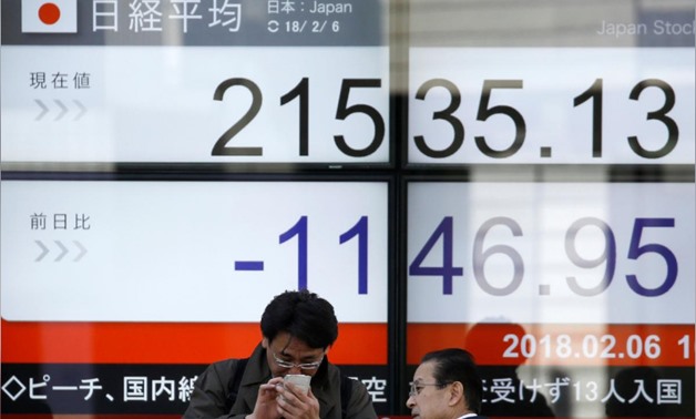Men look at a mobile phone in front of an electronic board showing Japan's Nikkei average outside a brokerage in Tokyo, Japan, February 6, 2018. REUTERS/Toru Hanai