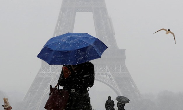 A woman holds an umbrella to protect herself from falling snow near the Eiffel Tower in Paris on Feb. 6, 2018. — Reuters 