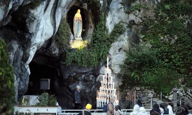 People pray at the Lourdes sanctuary, in the Massabielle cave where the Virgin Mary is said to have appeared to Bernadette Soubirous (AFP Photo/REMY GABALDA)
