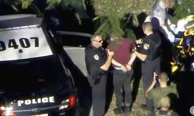 A man placed in handcuffs is led by police near Marjory Stoneman Douglas High School following a shooting incident in Parkland, Florida, on Wednesday. Police said the suspect was a 19-year-old former student at the school. Video still: WSVN.com via REUTER