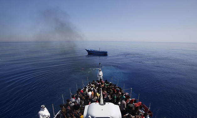 RESCUED: Italian police carry migrants to safety, leaving their leaky boat to drift. REUTERS/Alessandro Bianchi
