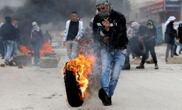 A Palestinian demonstrator kicks a burning tyre during clashes with Israeli troops in Halhoul, in the occupied West Bank February 17, 2018. REUTERS/Mussa Qawasma