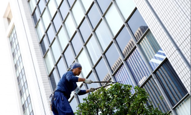 FILE PHOTO: A worker cuts a tree in front of an office building at a business district in Tokyo, Japan, May 18, 2016. REUTERS/Thomas Peter/File Photo
