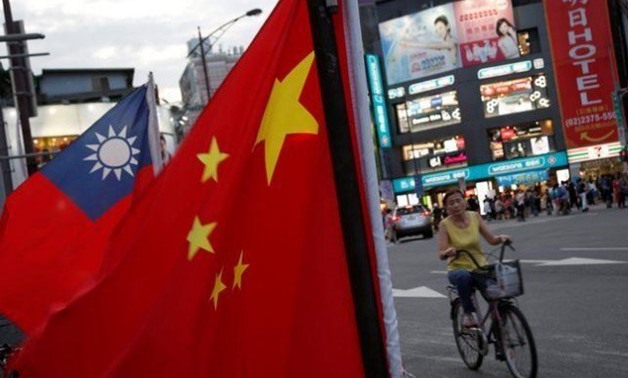 A woman rides a bike past Taiwan and China national flags during a rally held in Taipei, Taiwan. PHOTO: REUTERS