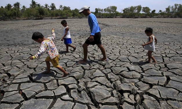 A father with his children walk over the cracked soil of a 1.5 hectare dried up fishery at the Novaleta town in Cavite province, south of Manila May 26, 2015. REUTERS/Romeo Ranoco/Files