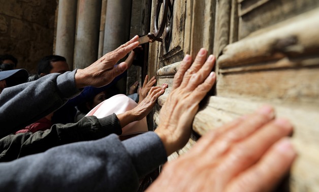 Worshippers touch the closed doors of the Church of the Holy Sepulchre in Jerusalem's Old City February 27, 2018. REUTERS/Ammar Awad