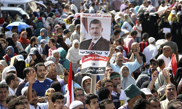 Supporters of MB President Mohamed Morsi, hold his posters as they rally at the Rabaa Adawia square where they are camping - REUTERS