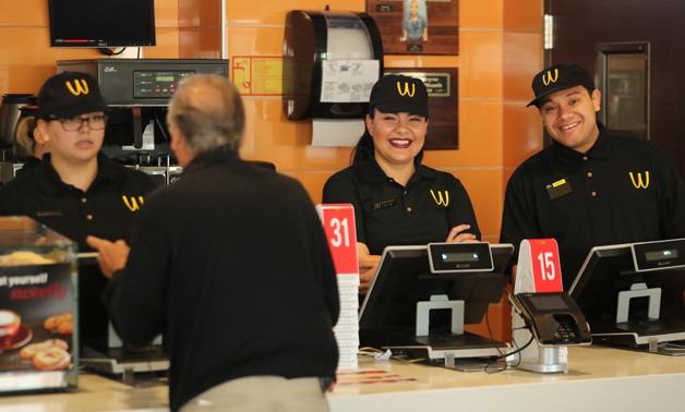 Workers greet customers as McDonald's iconic 'M' logo is turned upside down in honour of International Women's Day in Lynwood, California, U.S., March 8, 2018. REUTERS/Mike Blake