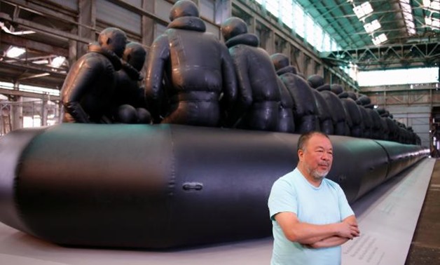 Chinese artist Ai Weiwei stands in front of his artwork consisting of a 60-metre rubber raft installation titled 'Law of the Journey' which includes around 300 figures representing refugees, during a media call for the Biennale of Sydney located in the in