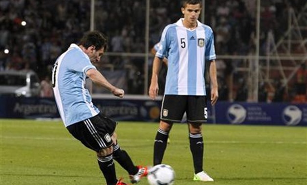 Argentina's Lionel Messi (L) kicks the ball to score his second goal against Uruguay as his teammate Fernando Gago looks on during their 2014 World Cup qualifying soccer match in Mendoza, October 12, 2012 – REUTERS/Enrique Marcarian 