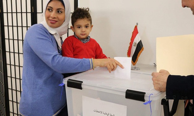 FILE: An Egyptian woman carries her son as she casts her ballot for the Presidential Vote at the polling station of the Egyptian Embassy in the United States 